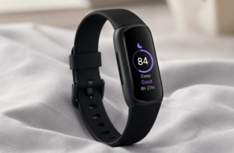Fitbit Inspire 3 black fitness band on light gray duvet showing sleep score 84