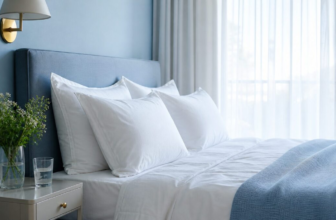 Crisp white pillows arranged on freshly made bed with sheer curtains and morning light
