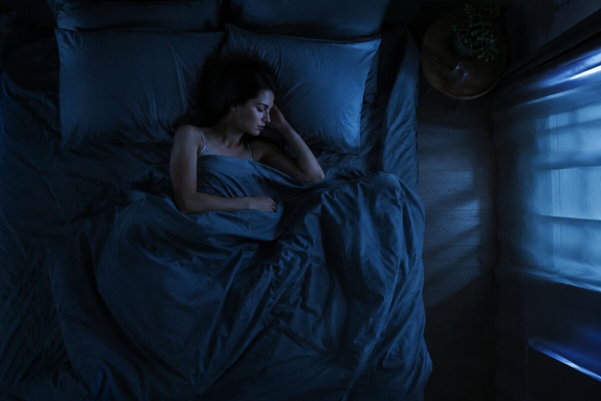 Person sleeping peacefully in a dark bedroom with moonlight, seen from above